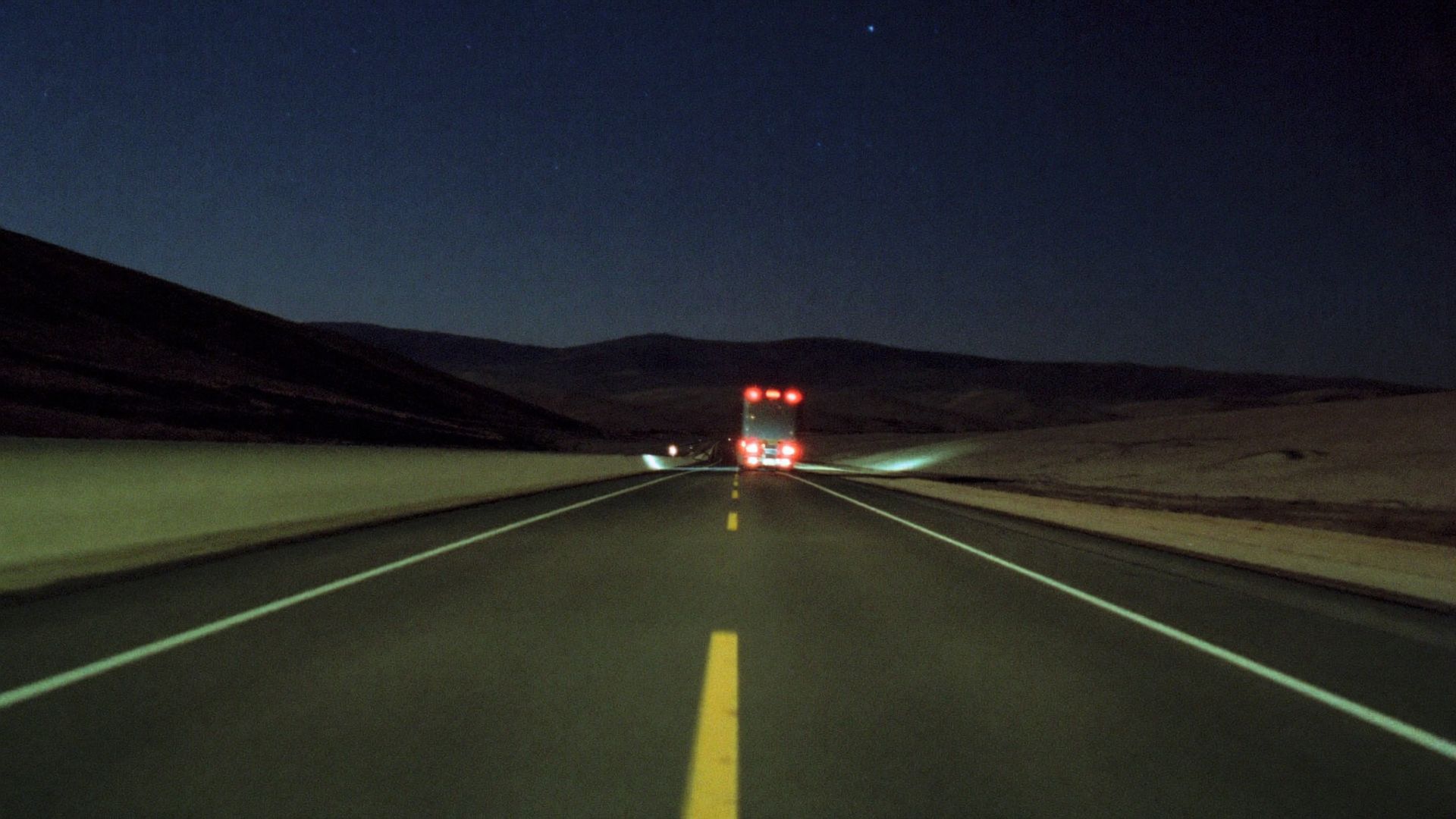 A highway at night stretching toward distant hills