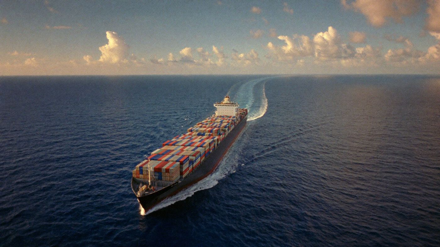 Container ship crossing open ocean at golden hour